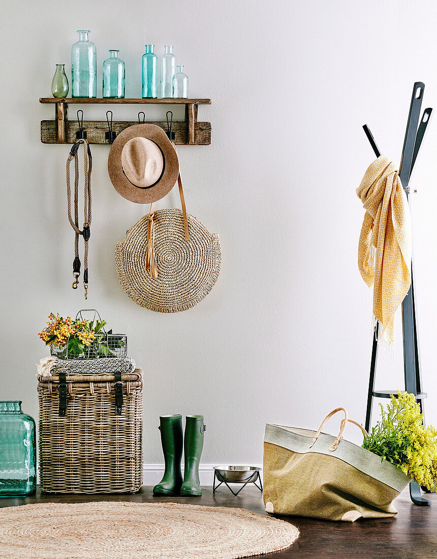 Wall coat rack with bottle collection, hat and handbag, including wicker chest and rubber boots, next to it a coat rack