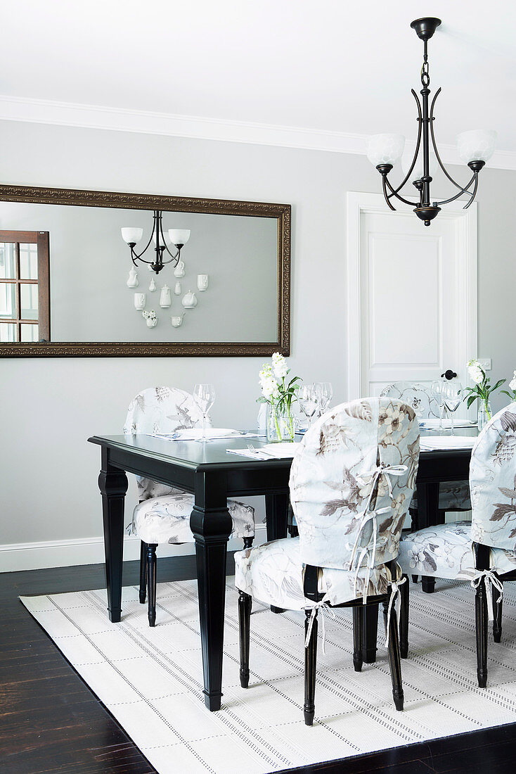 Eleganter Essbereich: dunkler Tisch, Stühle mit Hussen und Wandspiegel