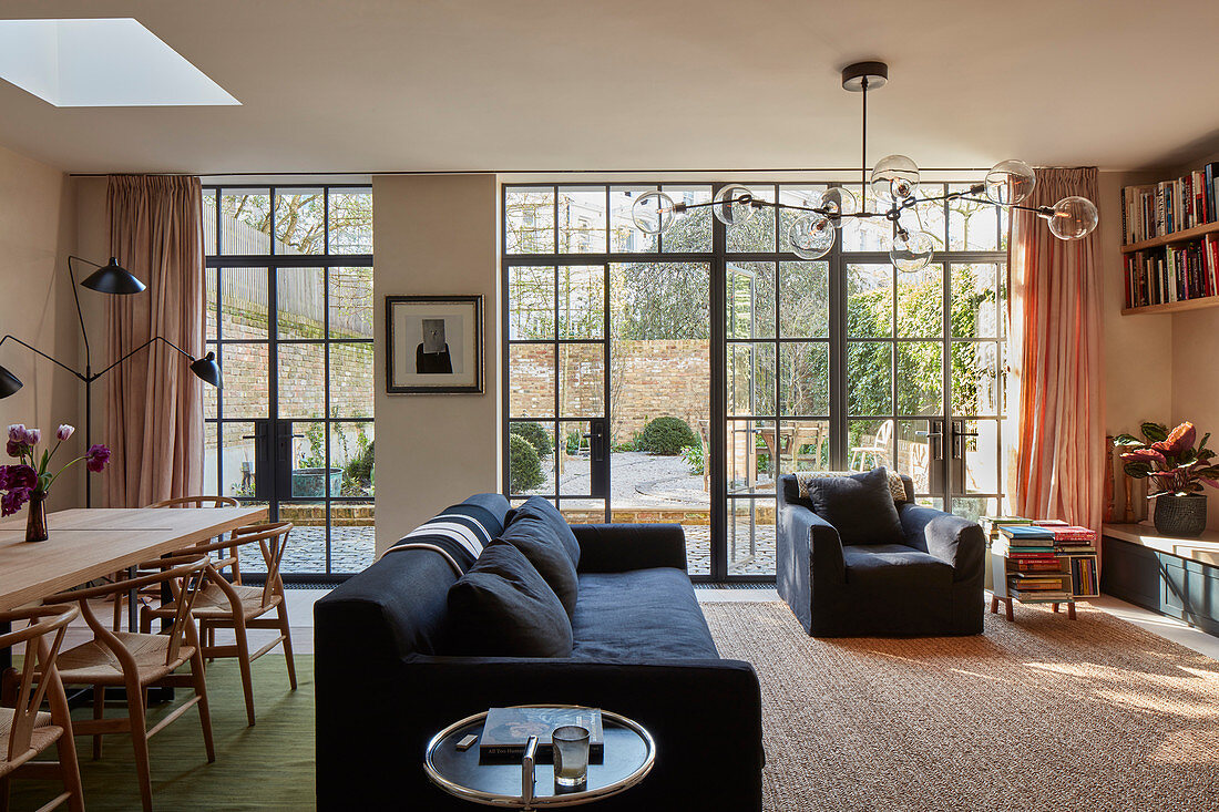 Offener Wohnraum mit Lounge und Essbereich vor Glasfront