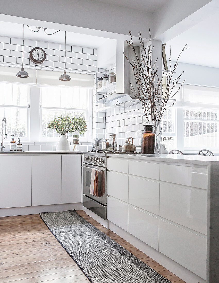 Offene Küche mit weißen Hochglanzfronten und Holzboden