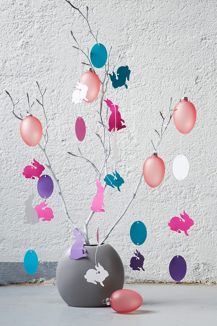Vase of branches decorated with paper cut-outs and Easter eggs