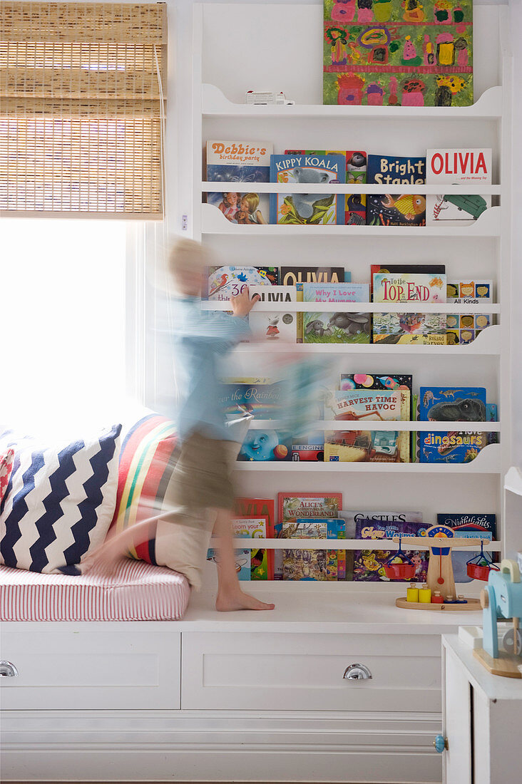 Junge bewegt sich vor dem Bücherregal im Kinderzimmer