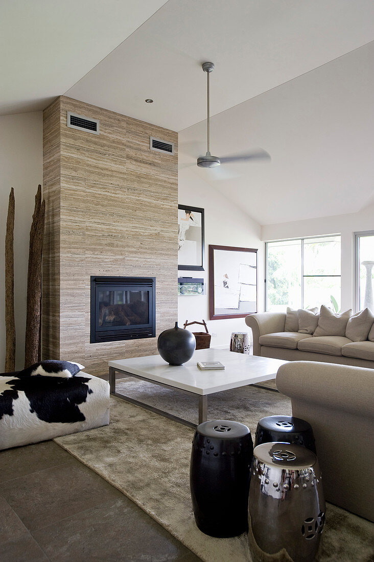 Helles Wohnzimmer mit beigefarbener Polstergarnitur, Kamin, Couchtisch und Beistelltischen