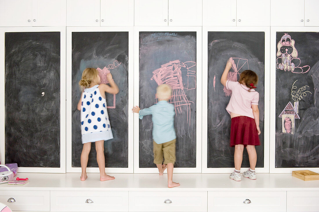 Children drawing on cupboards with chalkboard doors