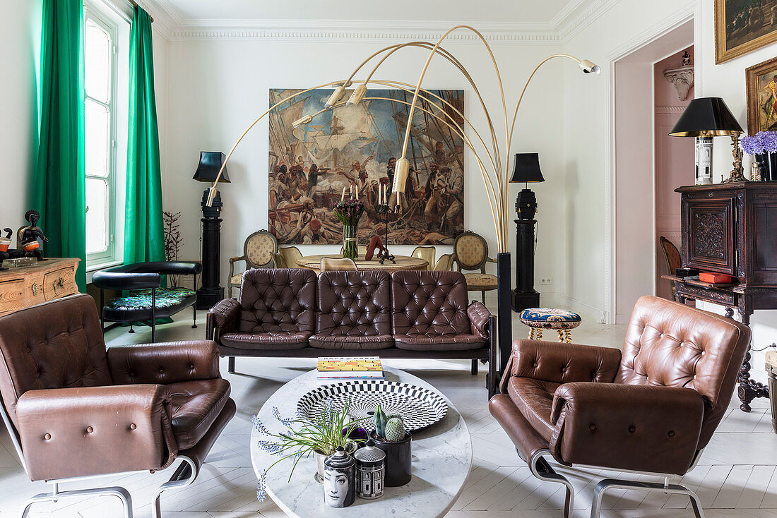 Braune Ledergarnitur und italienische Designerleuchte im Wohnzimmer, im Hintergrund großformatiges Gemälde