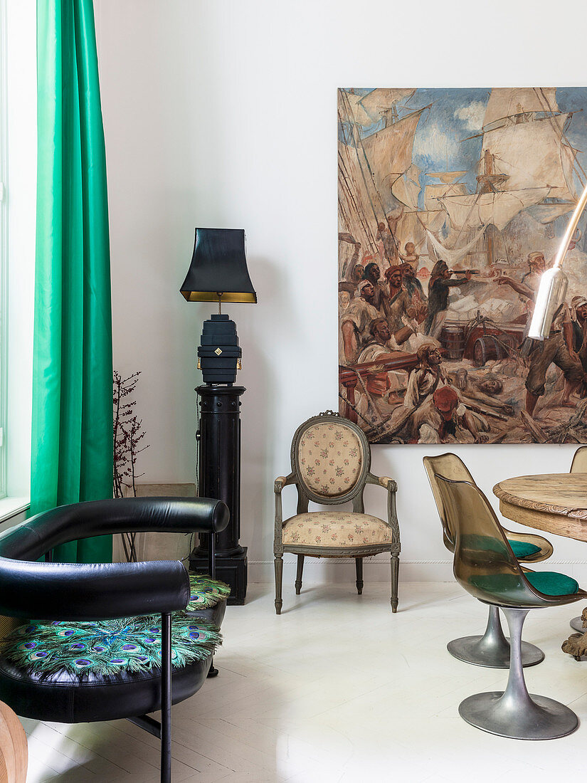 Schwarze Lederbank, Tischlampe auf Säule, Stuhl und Gemälde im Essbereich mit Klassikerstühlen
