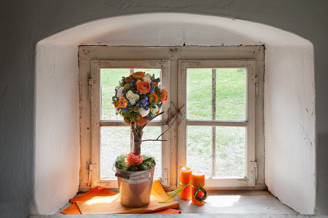 Tree-shaped flower arrangement on sill of rustic window