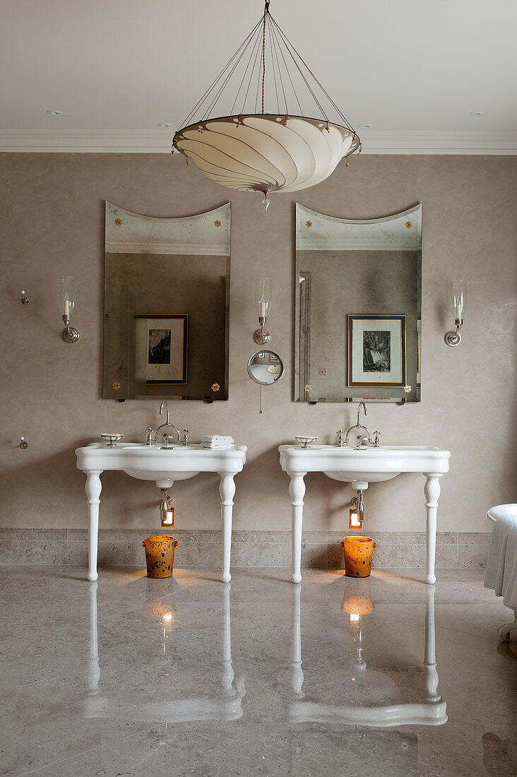 Pair of 20th century basins in bathroom with grey marbled floors, wall mirrors and silk lampshade