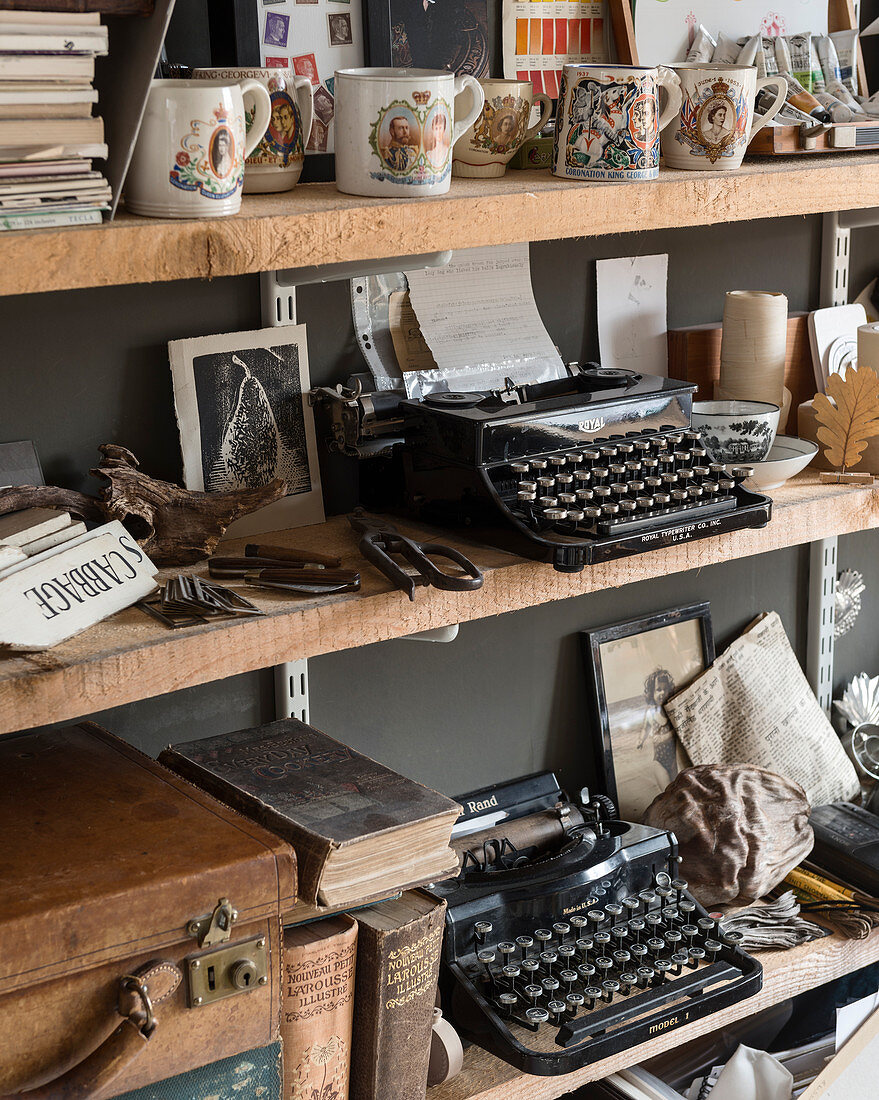 Alte Schreibmaschinen, Krönungsbecher und verschiedene Bücher in offenem Regal