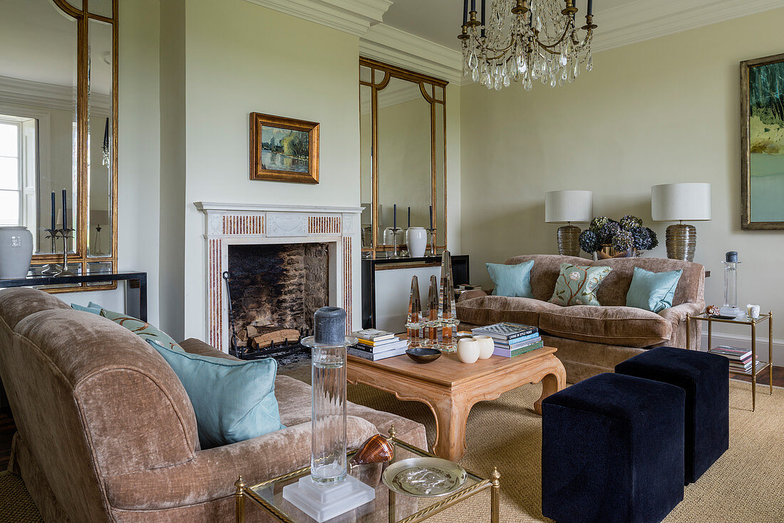 Large antique mirrors in airy sitting room with fireplace and pair of sofas upholstered in taupe linen velvet