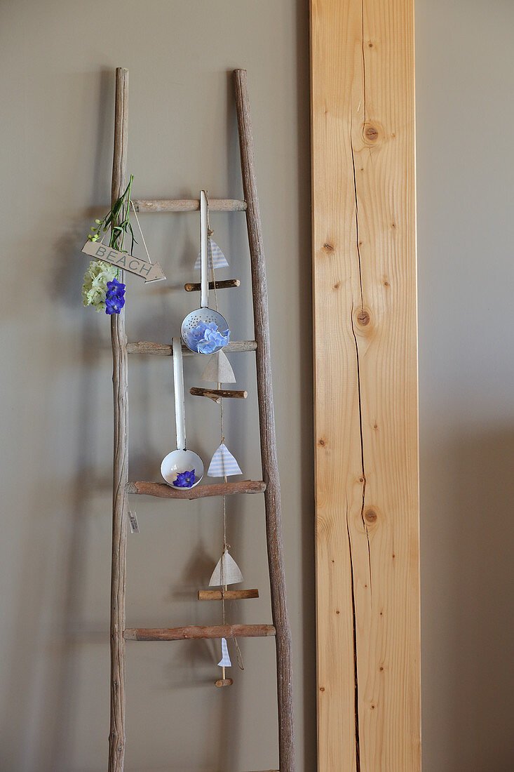 Handcrafted wooden ladder holding flower arrangements and garland of paper boats