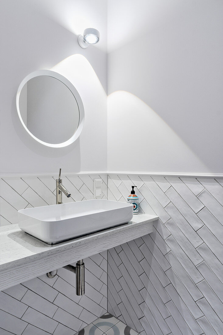 White bathroom with walls tiled to half height with subway tiles
