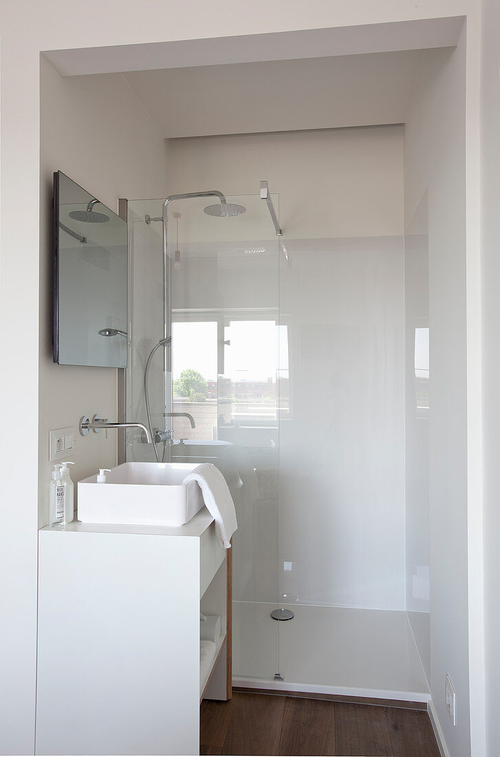 White washstand with countertop sink and shower area in small bathroom