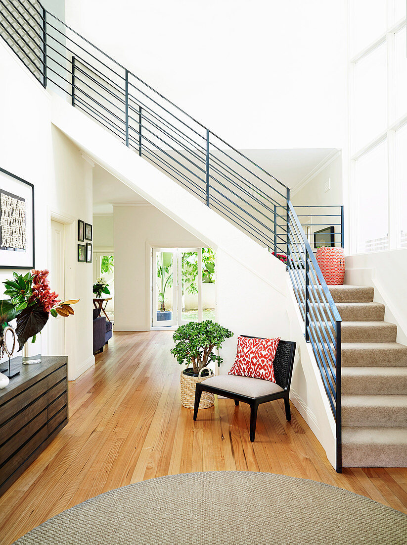 Bright hallway with wooden floor under the stairs with metal railings