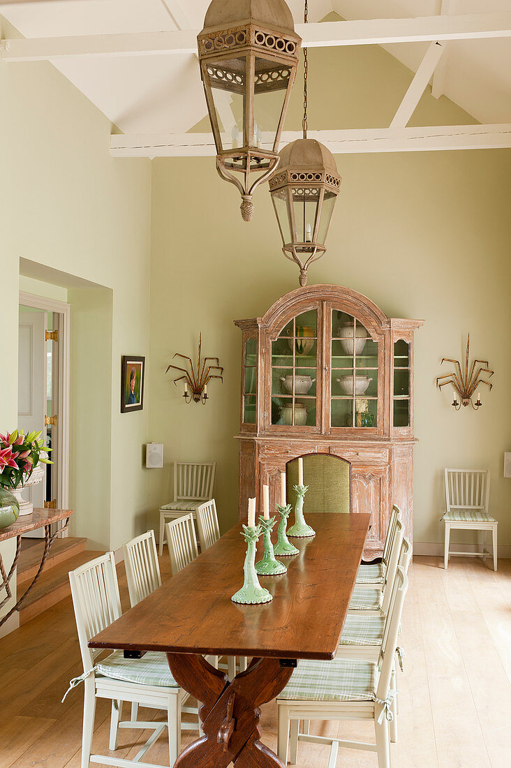 Weiße schwedische Stühle um Esstisch aus Holz und antike französische Anrichte in hellem Esszimmer