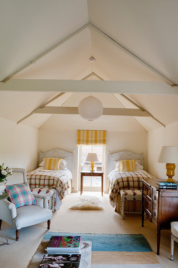 Attic twin bedroom with beamed ceiling, yellow striped matching blinds and cushions and blue armchairs