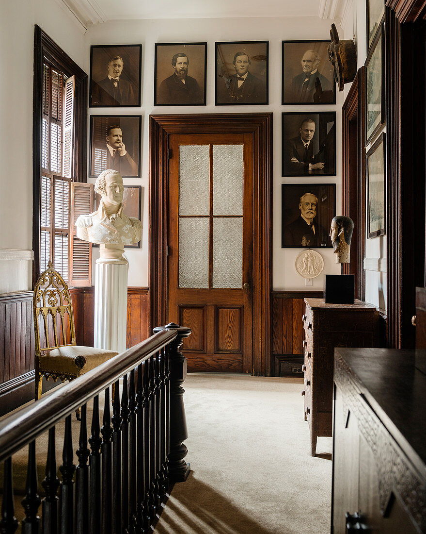 Early 20th century photographs on landing with velvet pile carpet, plaster bust of George Washington and glass panelled door