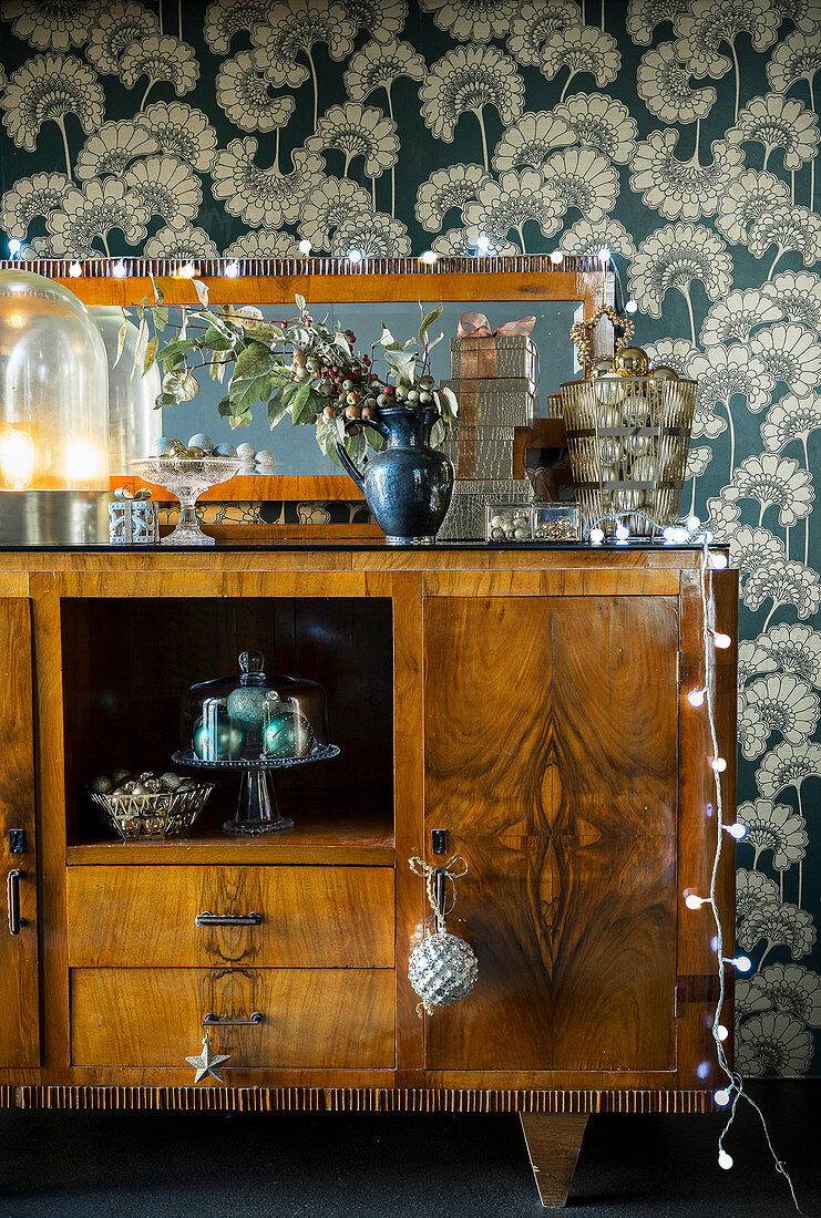 Festive decorations on old sideboard against vintage-style wallpaper