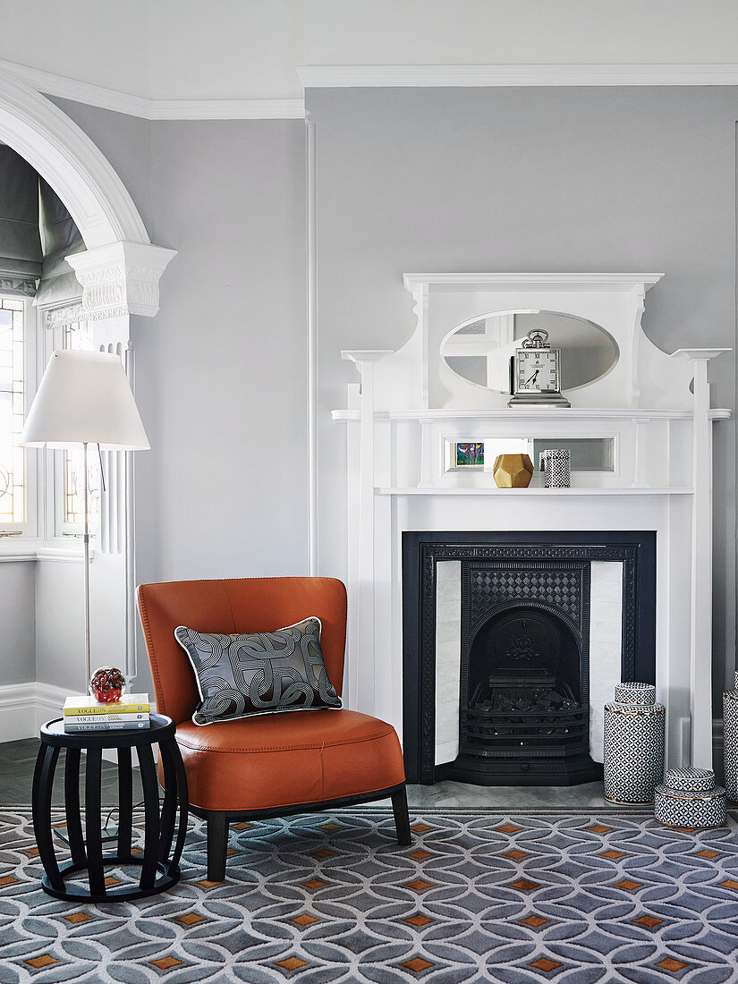 Cognacfarbener Lederstuhl und Beistelltisch vor Kamin im Wohnzimmer mit hellgrauer Wand