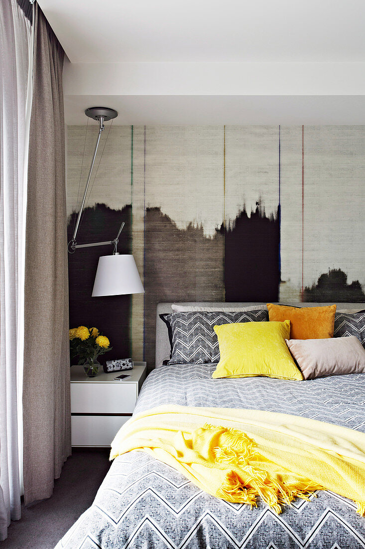 Doppelbett, Nachttisch und Lampe im Schlafzimmer mit Textiltapete an der Wand