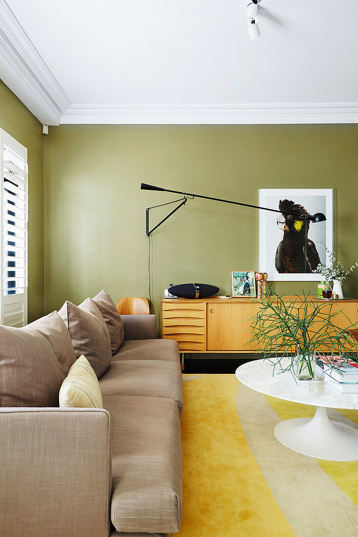 Sofa, Sideboard und Klassikertisch im Wohnzimmer mit grünen Wänden