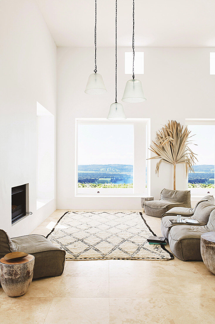 Polstermöbel und Teppich vor Kamin in weißem Wohnzimmer mit Meerblick