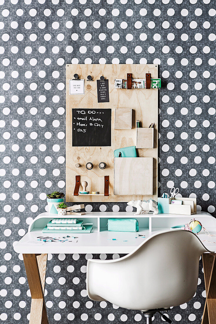 DIY-Pinnwand über Schreibtisch mit weißem Schalenstuhl