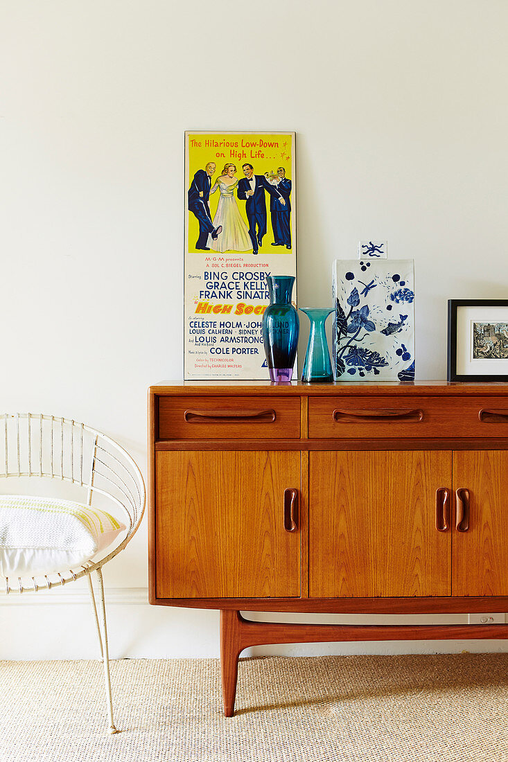 Retro sideboard with poster and vases, chair next to it