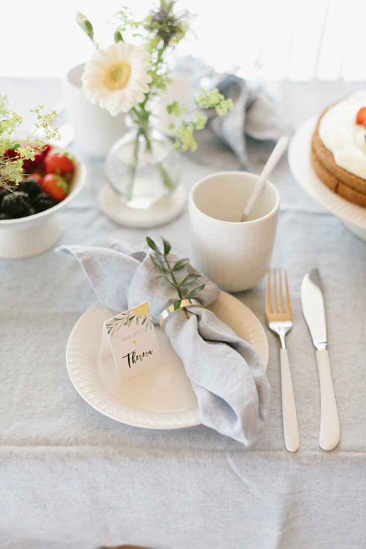 Place setting with linen napkin and name card on table set for afternoon coffee