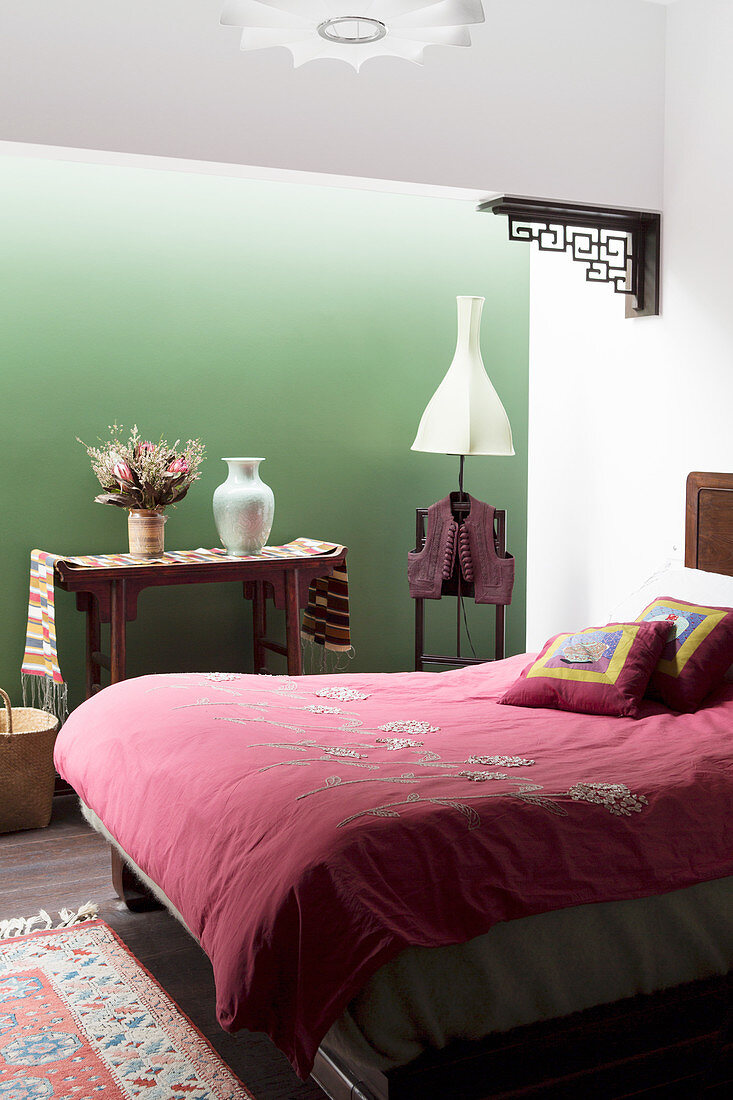 Doppelbett im Schlafzimmer mit grüner Wand