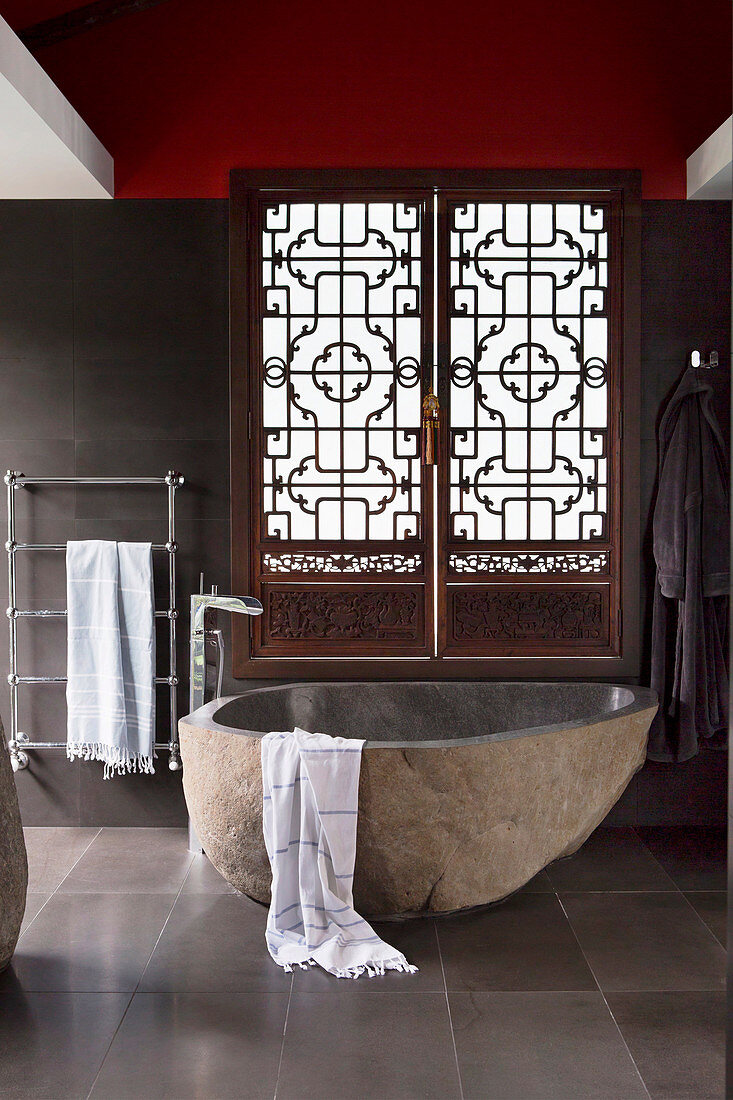 Badewanne aus Basalt und verzierter, antiker Fensterladen im Designerbadezimmer