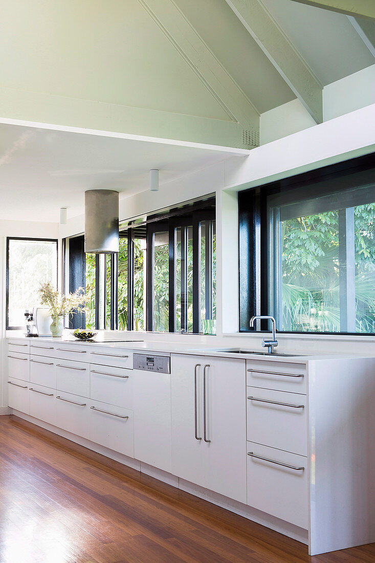 weiße Küchenzeile unter Fenstern in heller Küche