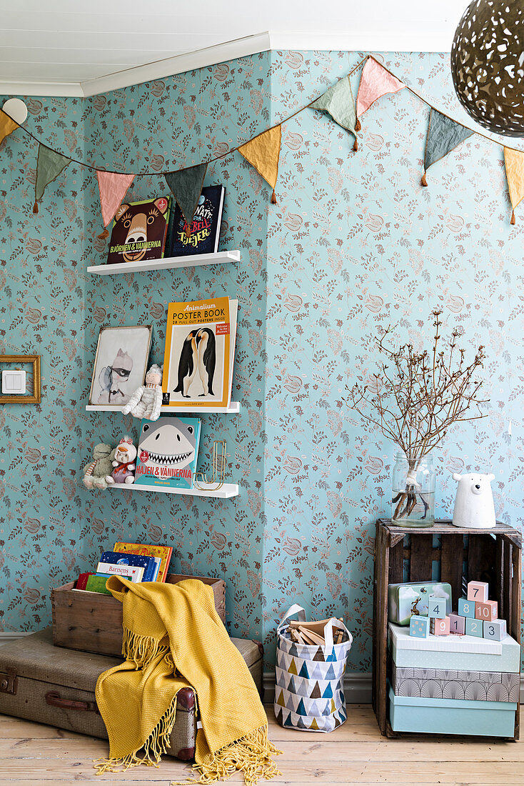 Bunting on wall with blue floral wallpaper in nursery