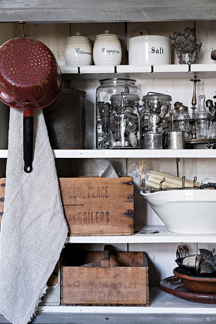 Kitchen utensils, cake tins and wooden crates on old shelving