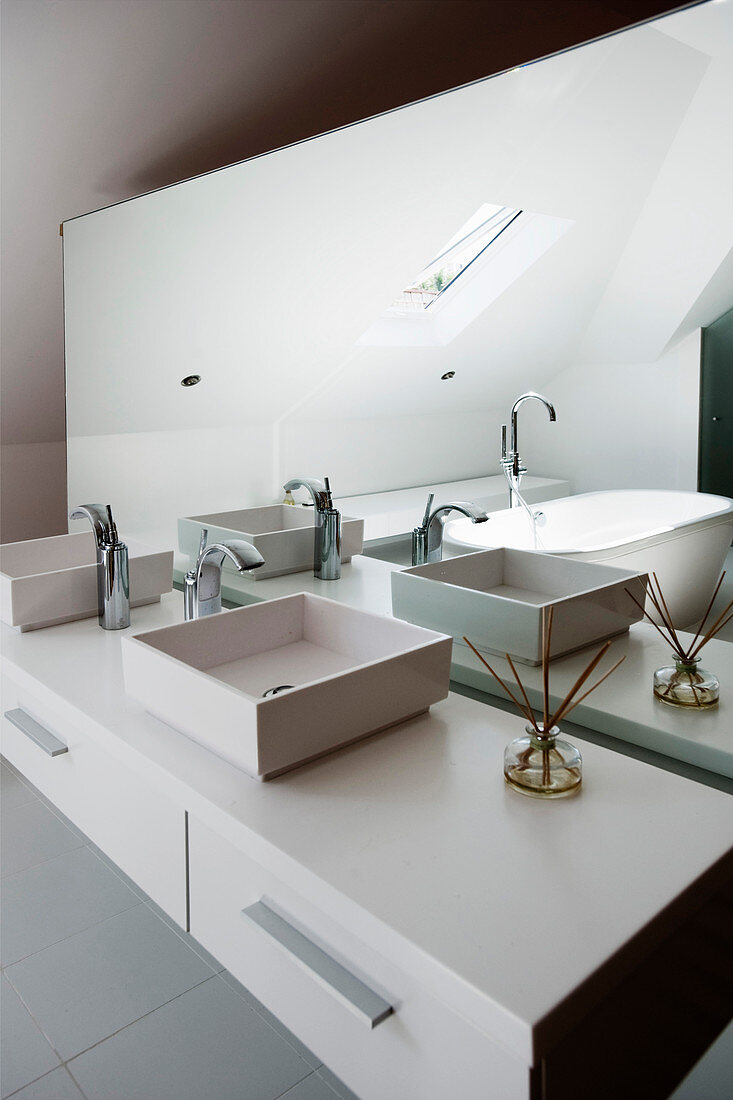Twin countertop sinks on washstand and mirrored partition wall in designer bathroom