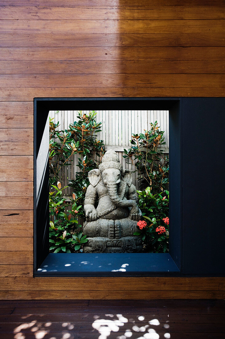 Blick durch Fenster auf Ganesha aus Lavastein im Garten