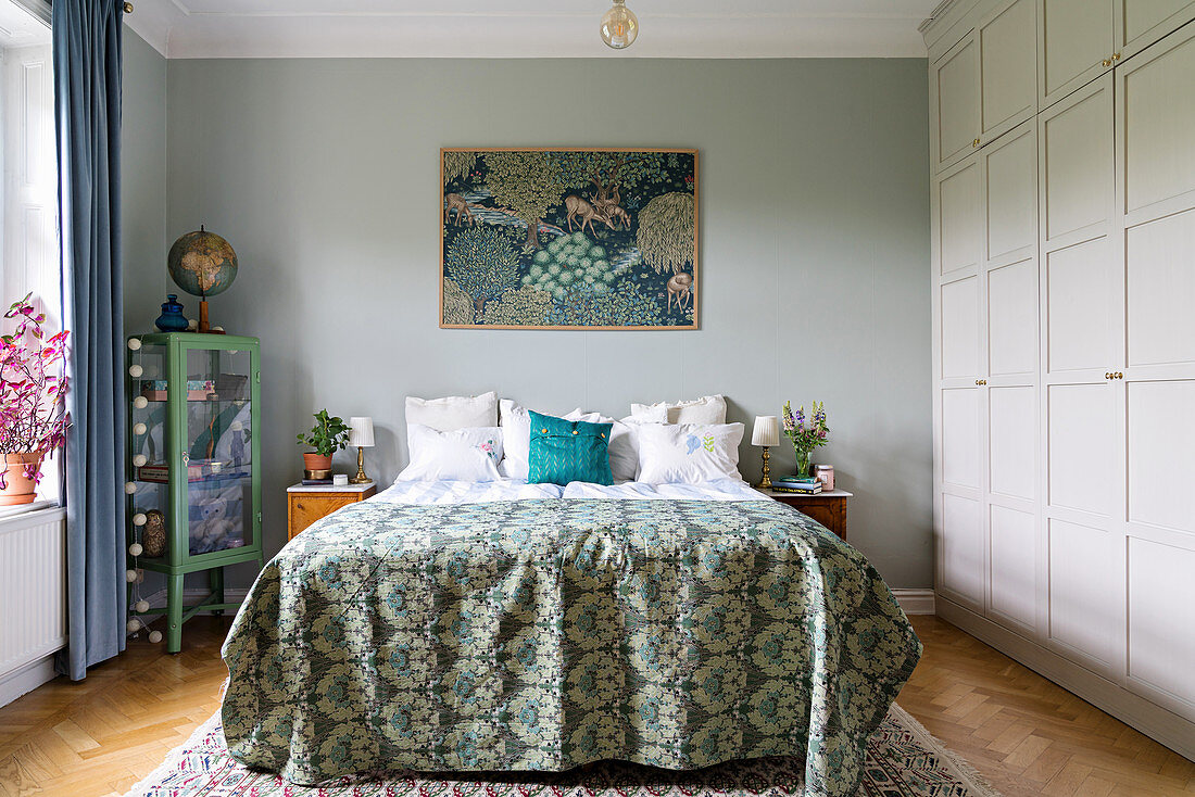 Double bed and floor-to-ceiling fitted wardrobes in bedroom in shades of blue and green
