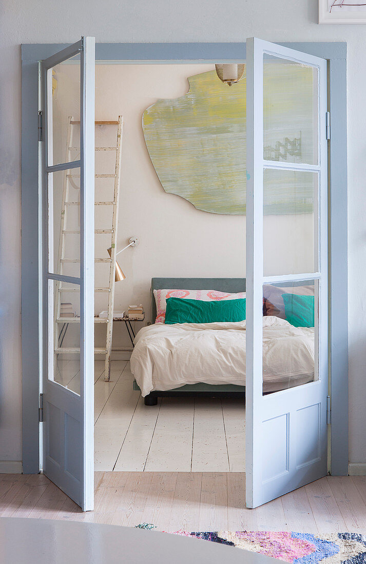 Open double doors with view into bedroom with board floor