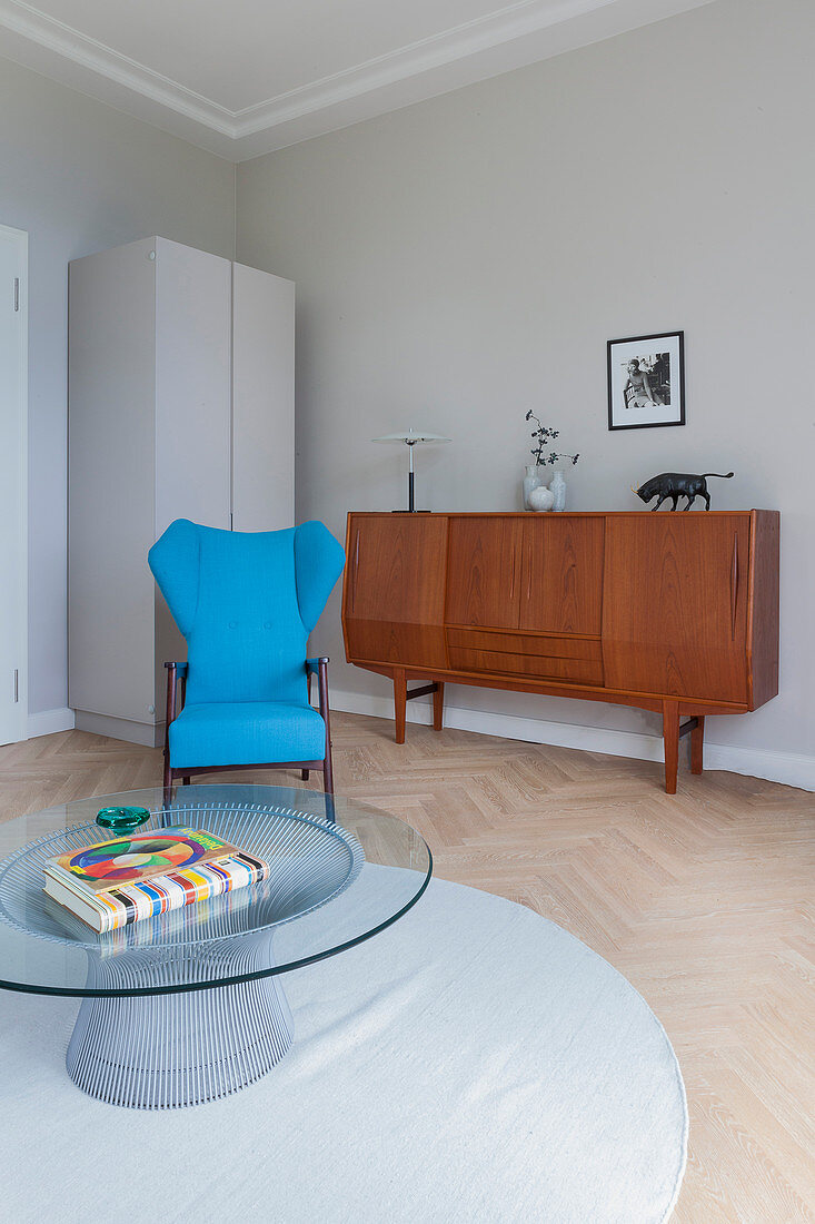 Runder Couchtisch, türkisblauer Sessel und Retro Sideboard im Wohnzimmer
