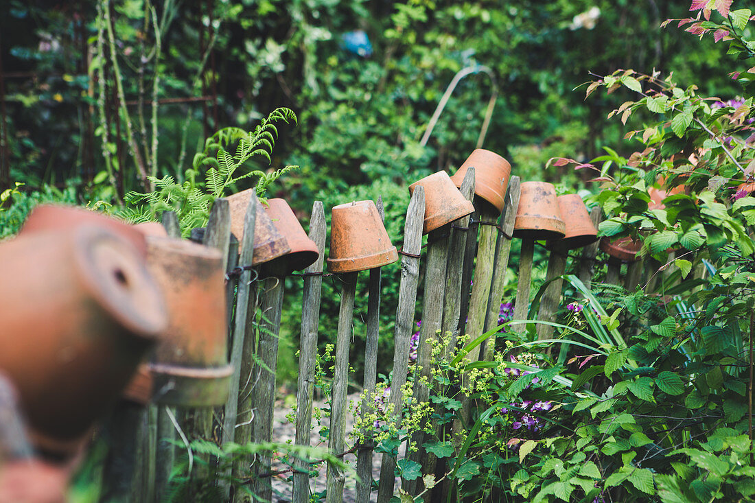 Clay pots on tops of garden fence stakes