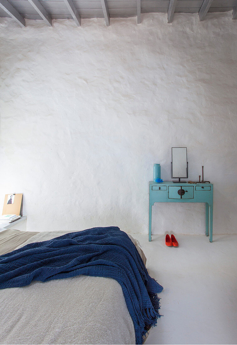 Doppelbett und türkisblauer Schminktisch in weiß gestrichenem Schlafzimmer