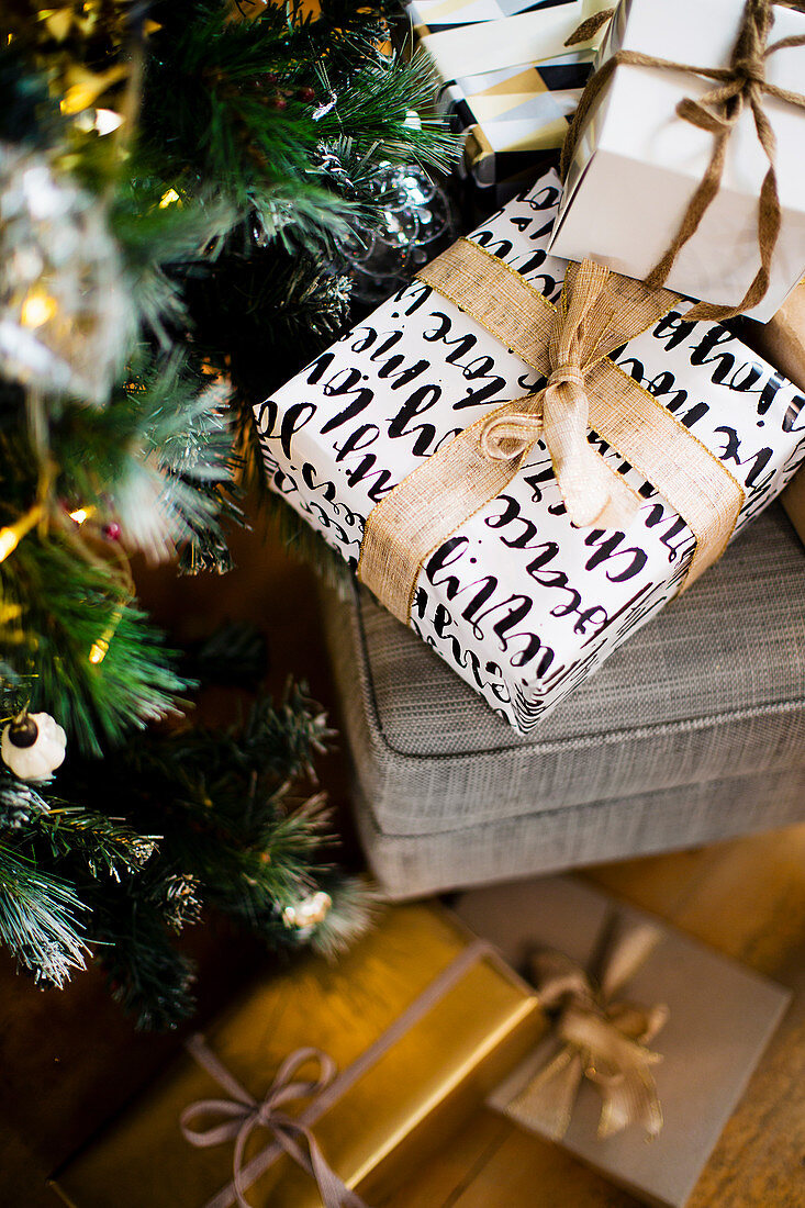 Verpackte Weihnachtsgeschenke unter und neben dem Tannenbaum