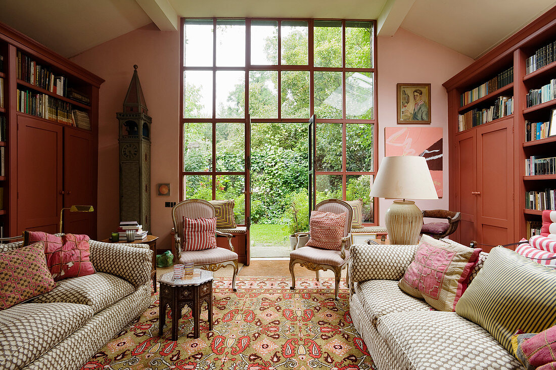 Couch, antique armchairs and bookcases in living room in shades of pink