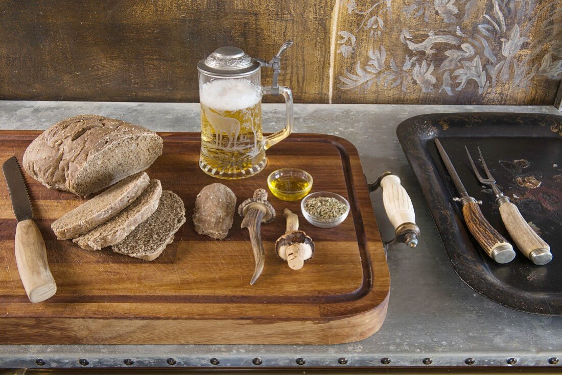 Aufgeschnittenes Brot auf Holztablett und Bierkrug mit Zinndeckel