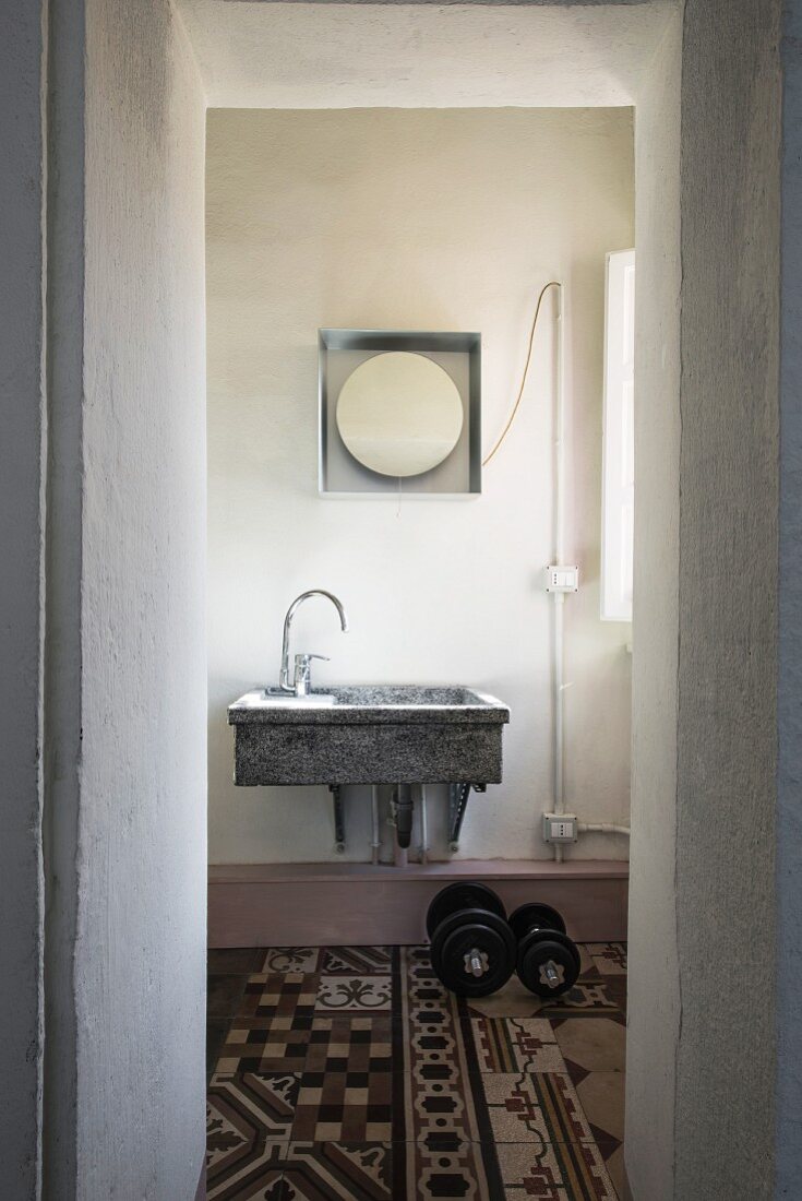 View of stone sink and tiles of various patterns seen through open door