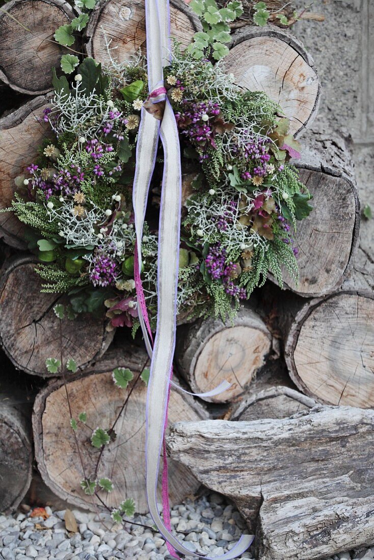 Autumnal wreath with lace ribbon on stack of weathered firewood