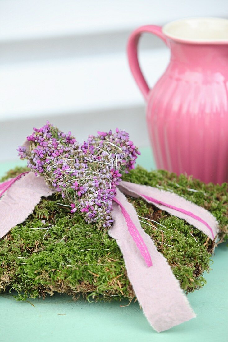 Romantisches Mooskissen mit rosa Stoffband und Herz aus Heidekraut
