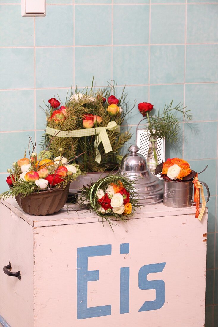 Flowers arranged in kitchen utensils on top of old ice-cream cart