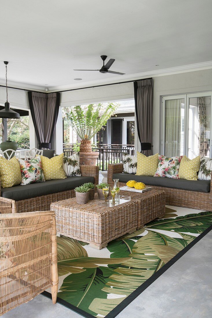 Rattan furniture on veranda with jungle-patterned rug