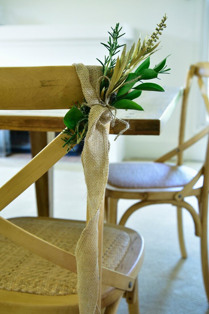 Green branches tied to chair back with strip of hessian